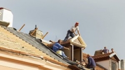 Workers on roof replacing shingles