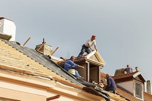 Workers on roof replacing shingles