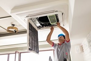 Contractor working on an HVAC system in the ceiling