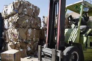 Forklift at recycling facility with bales of cardboard