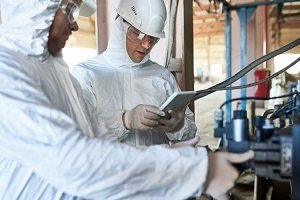 Two men in white protective suits and gloves testing equipment