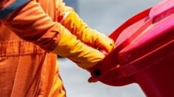 Person wheeling a red disposal bin