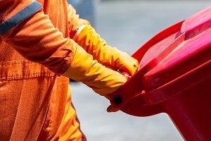 Person wheeling a red disposal bin