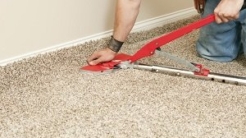 Carpet contractor installing new carpet with tool