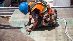 Roofer installing shingles on roof