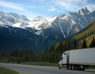 Large truck driving on highway with mountains in background