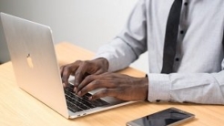 Man in tie typing on laptop