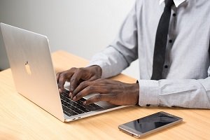 Man in tie typing on laptop