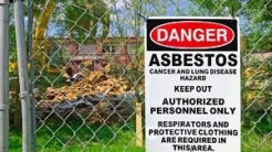 Sign hanging on a chain link fence that says Danger Asbestos