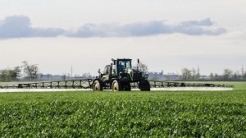 Tractor spraying liquid fertilizer in green field