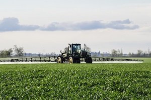 Tractor spraying liquid fertilizer in green field