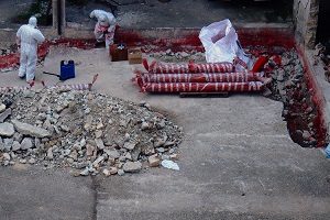 Remediation workers in protective suits handling debris