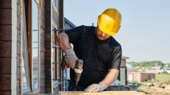 Man in hardhat drilling wood