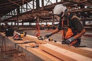 Man in gloves and hardhat cutting wood